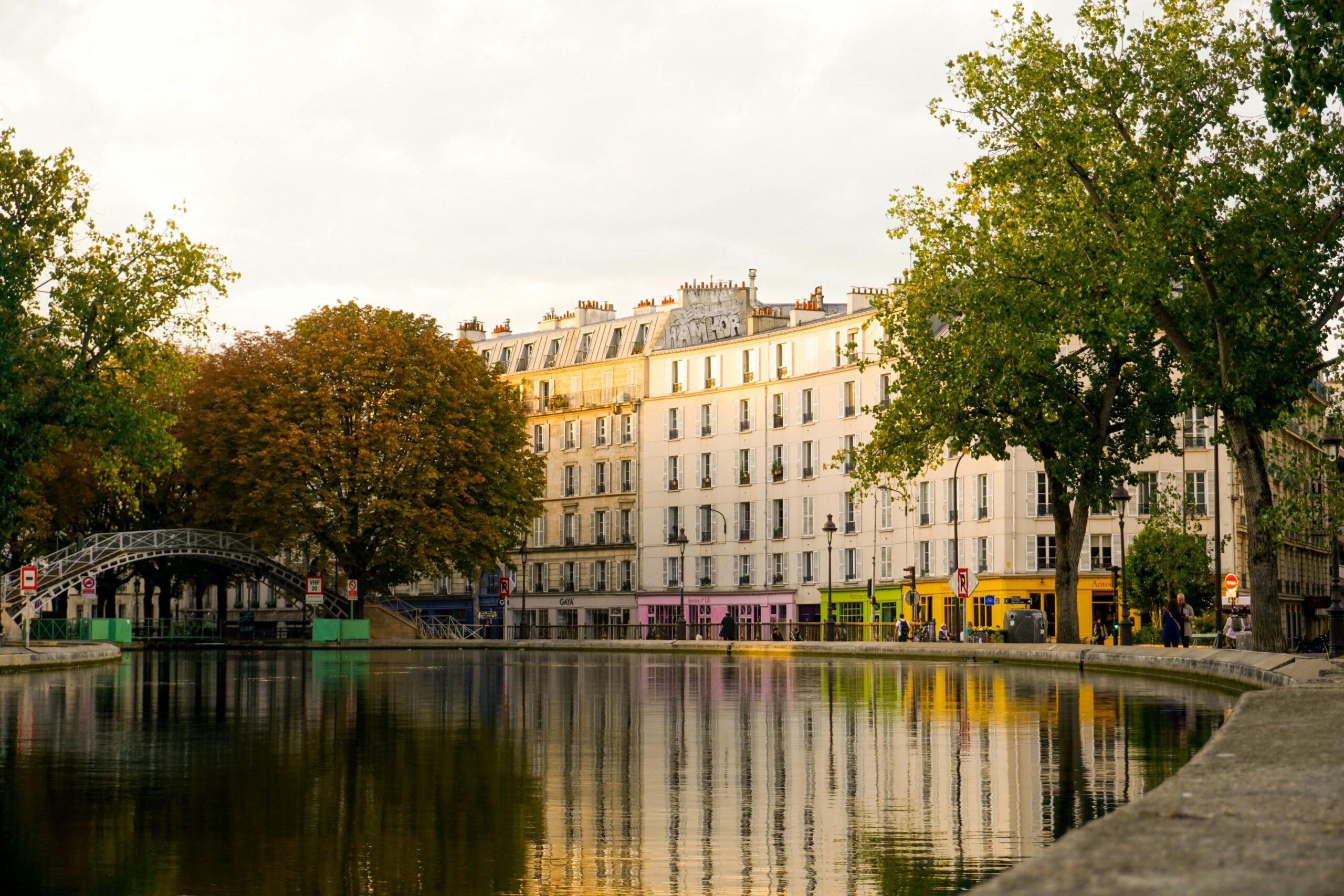 Vue du canal Saint-Martin à Paris avec les boutiques colorées d’Antoine & Lili en arrière-plan, dans le quartier animé du 10e arrondissement.