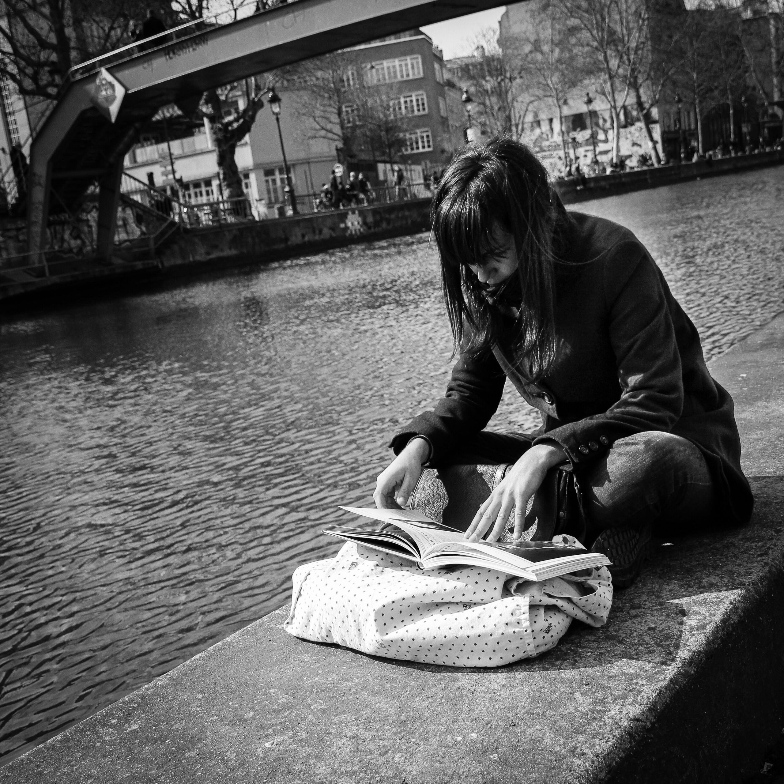 Femme lisant un livre au bord du canal Saint-Martin à Paris, lieu emblématique de détente dans le 10e arrondissement.