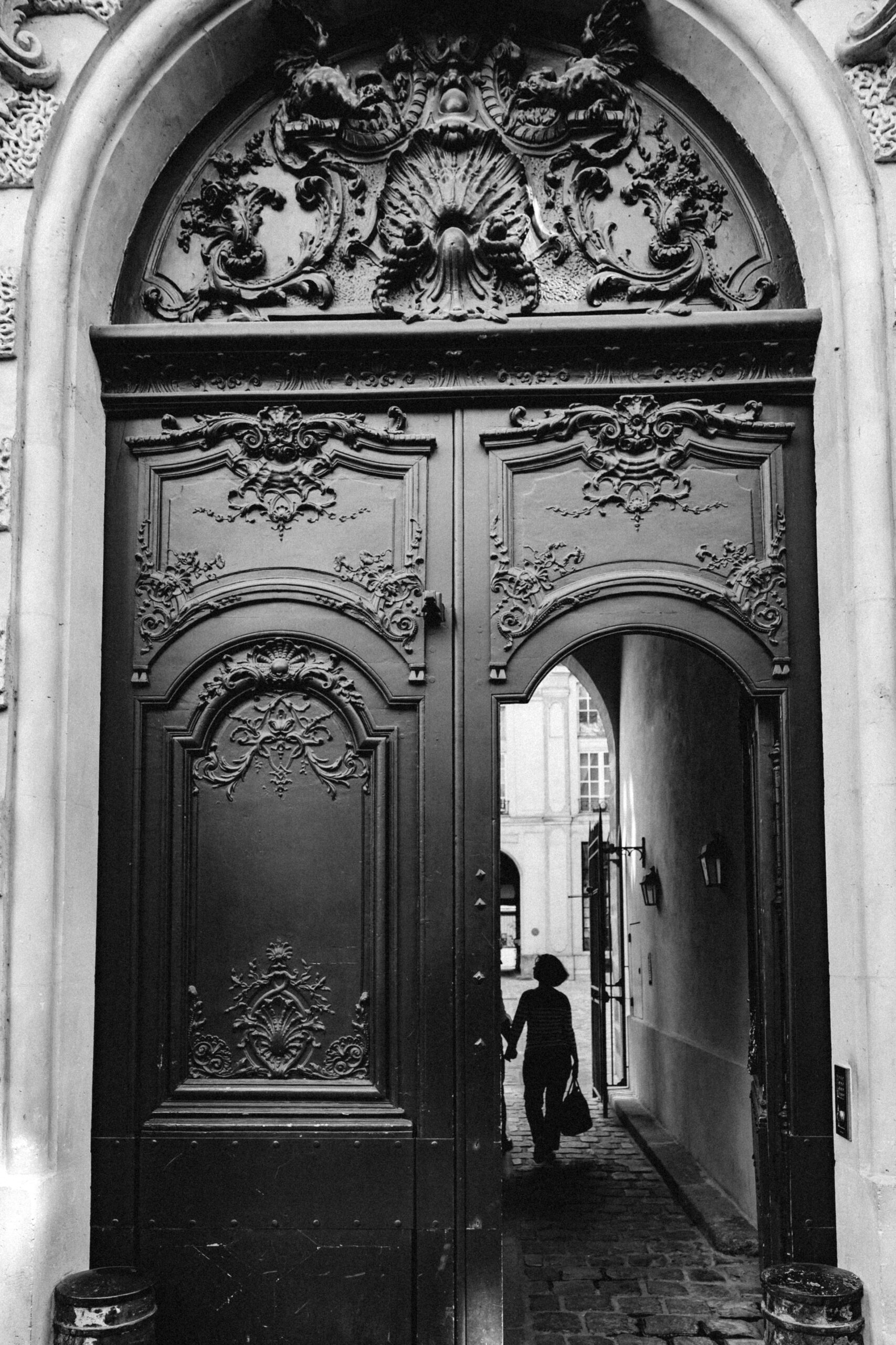 Porte cochère parisienne ornée de détails architecturaux classiques, illustrant le charme des rénovations haut de gamme proposées par Venor Immobilier à Paris