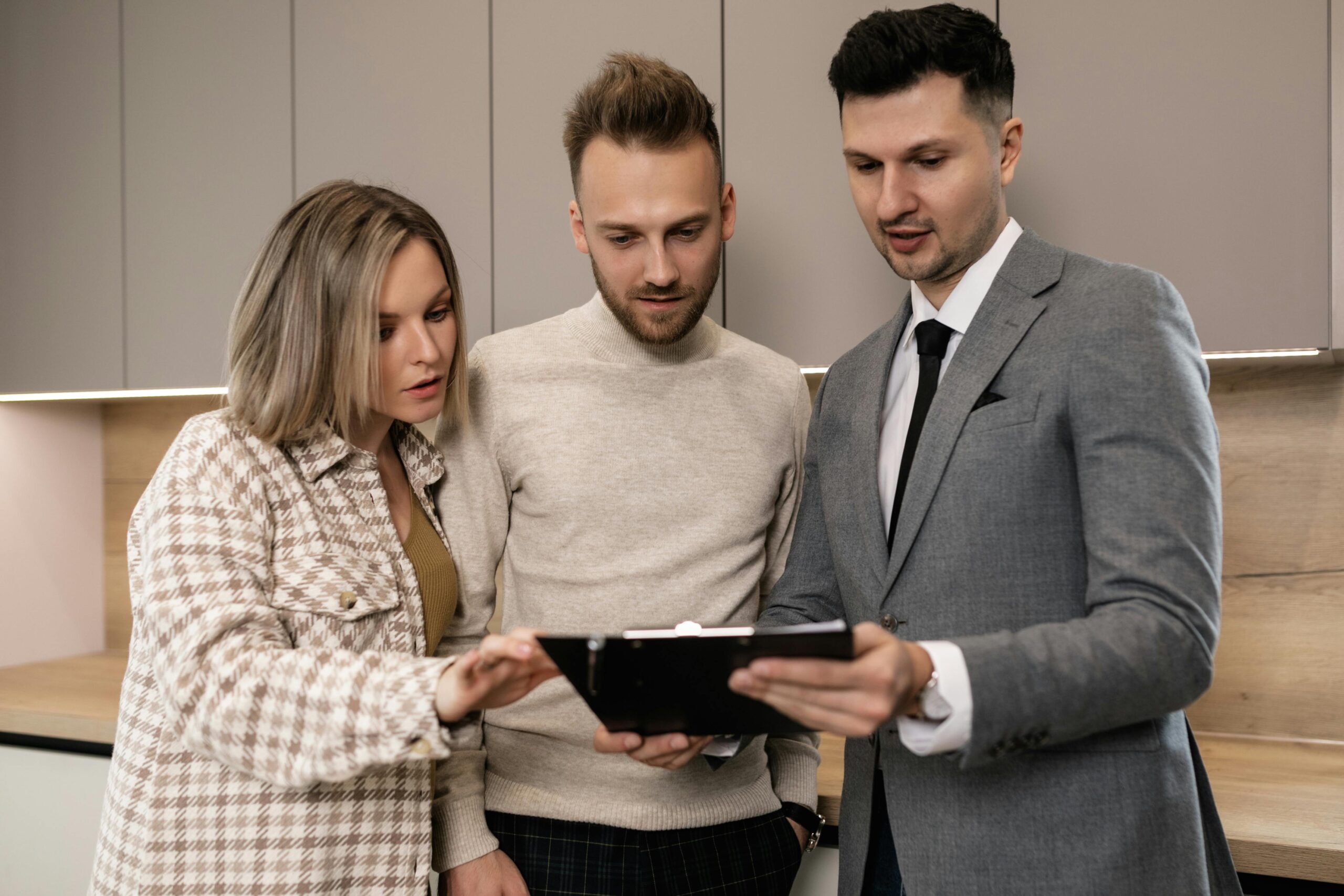 Agent immobilier montrant des documents de financement à un couple intéressé par l’achat immobilier.